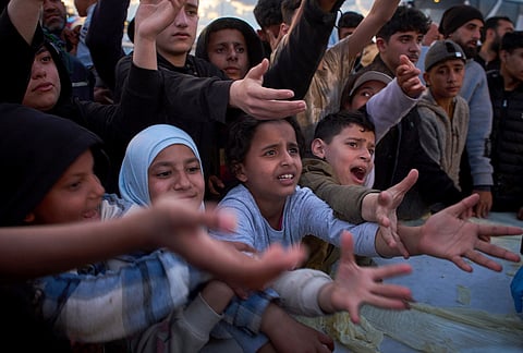 Displaced people wait to receive donated food beside the tents they use as shelters after fleeing Israeli bombardment in southern Lebanon, in Beirut, Lebanon,.