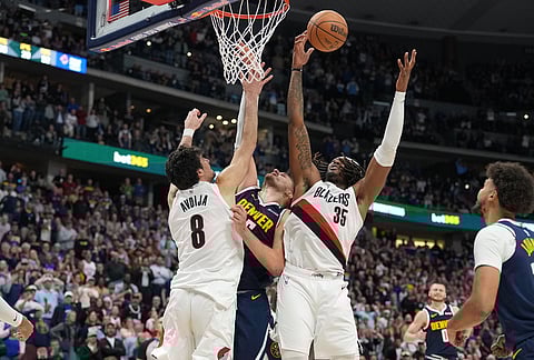 Portland Trail Blazers center Robert Williams III grabs the ball as forward Deni Avdija, left, blocks Denver Nuggets center Nikola Jokic as he puts up a shot as time runs out in the second half of an NBA basketball game, in Denver.
