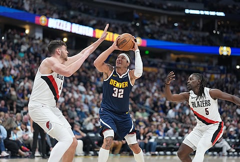 Denver Nuggets forward Aaron Gordon, center, drives to the basket between Portland Trail Blazers center Donovan Clingan, left, and guard Jrue Holiday in the second half of an NBA basketball game in Denver. 