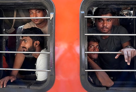 Young men look out from the crowded train window after just boarding, their faces tired, sitting packed inside the general coach.