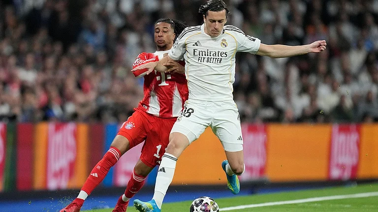 Real Madrid's Alvaro Carreras, foreground, and Bayern's Michael Olise challenge for the ball during the Champions League quarterfinal first leg soccer match between Real Madrid and Bayern Munich in Madrid, Spain, Tuesday, April 7, 2026 - AP Photo/Bernat Armangue