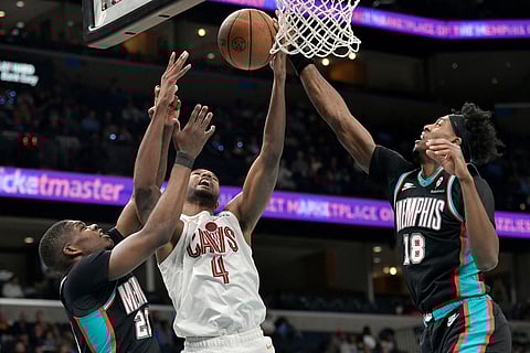 Cleveland Cavaliers center Evan Mobley (4) shoots between Memphis Grizzlies forwards Cedric Coward (23) and Olivier-Maxence Prosper (18) in the first half of an NBA basketball game in Memphis, Tenn.