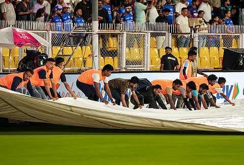 Ground staff cover the pitch during rain interruption in an Indian Premier League (IPL) 2026 T20 cricket match between Rajasthan Royals and Mumbai Indians, in Guwahati.