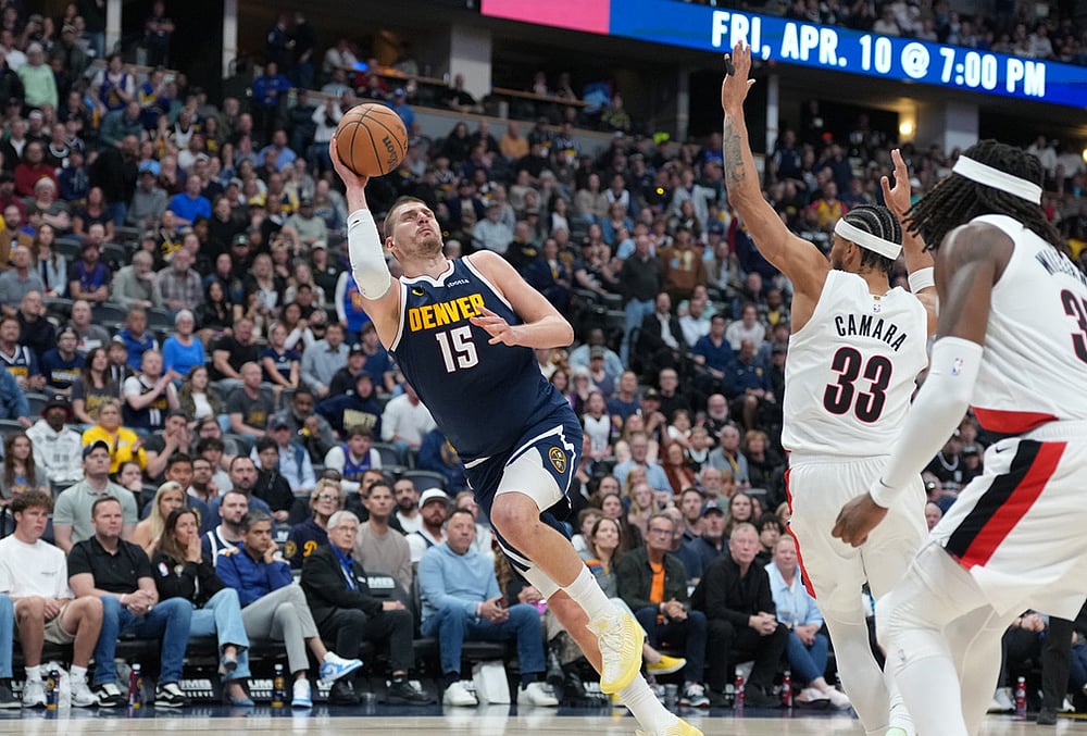 Denver Nuggets center Nikola Jokić, left, falls as he puts up a shot after being fouled by Portland Trail Blazers forward Toumani Camara, back right, as center Robert Williams III looks on in the second half of an NBA basketball game in Denver.  - | Photo: AP/David Zalubowski