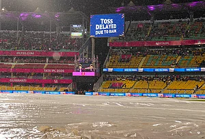 | Photo: PTI/Swapan Mahapatra : View of the ground covered due to rain as a screen displays 'Toss delayed due to rain' during an Indian Premier League (IPL) 2026 T20 cricket match between Rajasthan Royals and Mumbai Indians, in Guwahati.