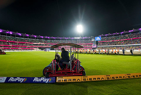 Ground staff cover the pitch during rain interruption in an Indian Premier League (IPL) 2026 T20 cricket match between Rajasthan Royals and Mumbai Indians, in Guwahati.