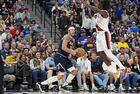 Denver Nuggets forward Aaron Gordon, left, avoids Portland Trail Blazers guard Jrue Holiday to set up for a three-point basket in overtime of an NBA basketball game, in Denver.