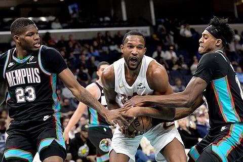 Cleveland Cavaliers center Evan Mobley, center, struggles for control of the ball against Memphis Grizzlies forwards Cedric Coward (23) and Olivier-Maxence Prosper, right in the first half of an NBA basketball game in Memphis, Tenn.