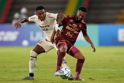 Jose Carabali of Peru's Universitario, left, battle the ball with Jersson Gonzalez of Colombia's Deportes Tolima during a Copa Libertadores Group B soccer match in Ibague, Colombia.
