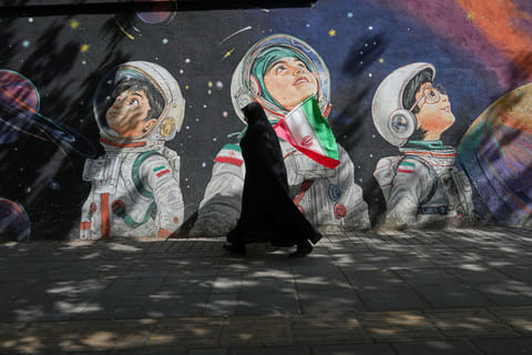 A woman walks past a mural in Tehran, Iran.