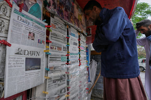 Pakistanis read morning newspapers, covering headlines news regarding United States Israel Iran war, at a stall in Islamabad, Pakistan.