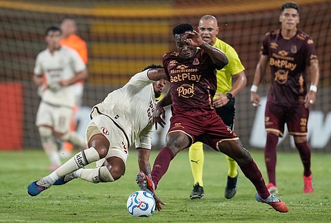 Adrian Parra of Colombia's Deportes Tolima, right, fights the ball with Jesus Castillo of Peru's Universitario during a Copa Libertadores Group B soccer match in Ibague, Colombia.
