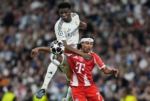 Real Madrid's Aurelien Tchouameni, top, and Bayern's Serge Gnabry challenge for the ball during the Champions League quarterfinal first leg soccer match between Real Madrid and Bayern Munich in Madrid, Spain.