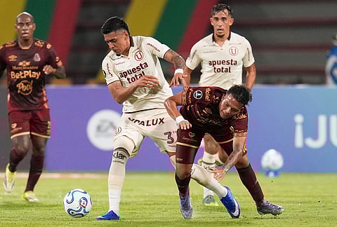 Cesar Inga of Peru's Universitario, left, fights the ball with Juan Torres of Colombia's Deportes Tolima during a Copa Libertadores Group B soccer match in Ibague, Colombia.