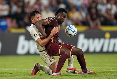 Cain Fara of Peru's Universitario, left, fouls Adrian Parra of Colombia's Deportes Tolima, during a Copa Libertadores Group B soccer match in Ibague, Colombia.