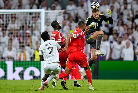Bayern's goalkeeper Manuel Neuer heads the ball to save before Real Madrid's Vinicius Junior, left, can score during the Champions League quarterfinal first leg soccer match between Real Madrid and Bayern Munich in Madrid, Spain.