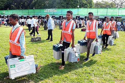 Polling officials carry Electronic Voting Machines (EVMs), Voter Verifiable Paper Audit Trail (VVPAT) and other election material as they depart for their respective polling booths on the eve of Assam Assembly Election, at a distribution centre, Tezpur, in Sonitpur.