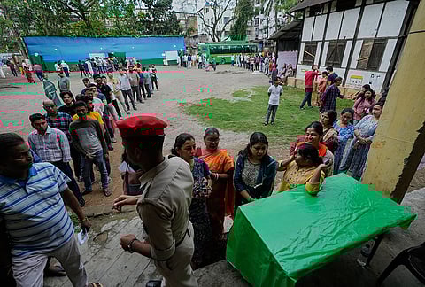 People stand in queue to cast their votes at a polling center during the state election in Guwahati.