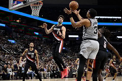 San Antonio Spurs forward Keldon Johnson (3) grabs the rebound ahead of Portland Trail Blazers' Jrue Holiday (5) and Deni Avdija (8) during the second half of an NBA basketball game in San Antonio.