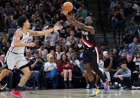 Portland Trail Blazers guard Jrue Holiday (5) grabs the ball ahead of San Antonio Spurs guard Dylan Harper during the first half of an NBA basketball game in San Antonio.