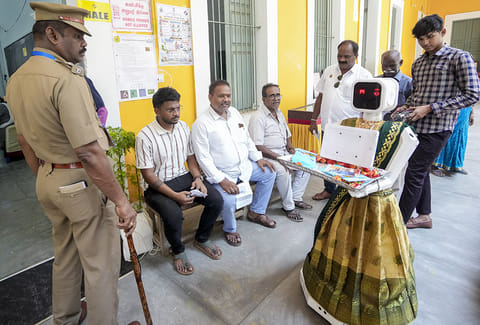 A man operates a robot while polling is underway during the Puducherry Assembly elections, at a polling station in Puducherry.