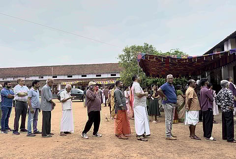 People queue up to vote outside a polling booth during the Kerala state election in Kochi.
