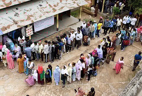 People wait in queues to cast their votes during the Assam Assembly elections, at a polling station, in Guwahati.