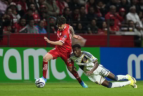 Emiro Garces of the United States' LA Galaxy, right, and Jesus Angulo of Mexico's Toluca vie for the ball during a CONCACAF Champions Cup quarterfinal first leg soccer match in Toluca, Mexico.