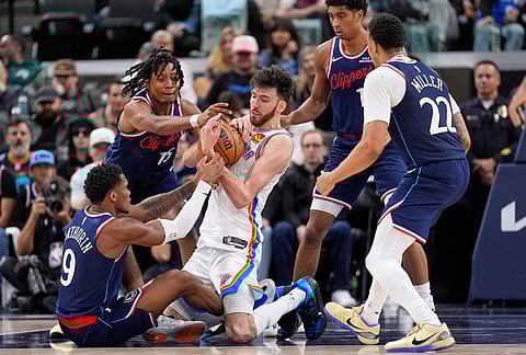 Oklahoma City Thunder center Chet Holmgren, center, battles for a loose ball with Los Angeles Clippers guard Bennedict Mathurin, left, and guard Tyty Washington Jr., second from left, as guard Cam Christie, second from right, and guard Jordan Miller watch during the second half of an NBA basketball game in Inglewood, California.