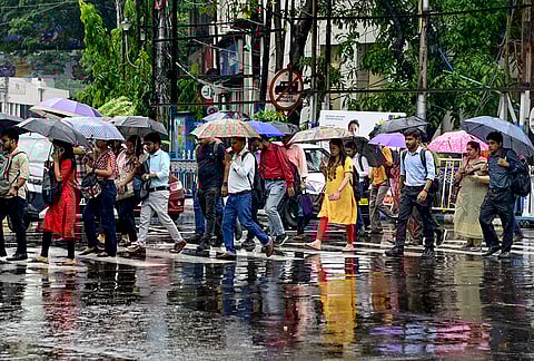 People cross a zebra crossing amid rainfall, in Kolkata, West Bengal.