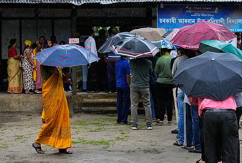 People stand in queue to cast their votes at a polling centre during the Assam state election in Guwahati.