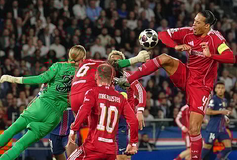 Liverpool's Virgil van Dijk, right, and PSG's goalkeeper Matvey Safonov challenge for the ball during the Champions League quarterfinal first leg soccer match between Paris Saint-Germain and Liverpool in Paris.