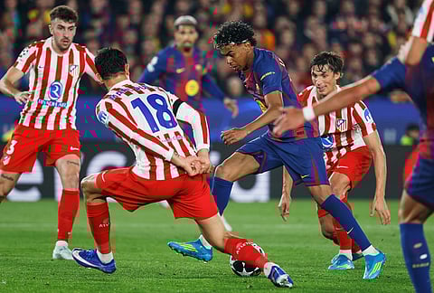 Barcelona's Lamine Yamal challenges for the ball with Atletico Madrid's Marc Pubill during the Champions League quarterfinal first leg soccer match between Barcelona and Atletico Madrid in Barcelona, Spain.