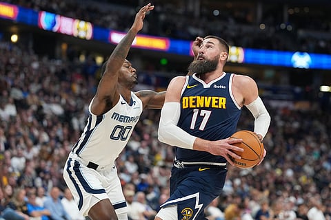 Denver Nuggets center Jonas Valanciunas, right, drives to the rim as Memphis Grizzlies forward Dariq Whitehead defends in the second half of an NBA basketball game in Denver.