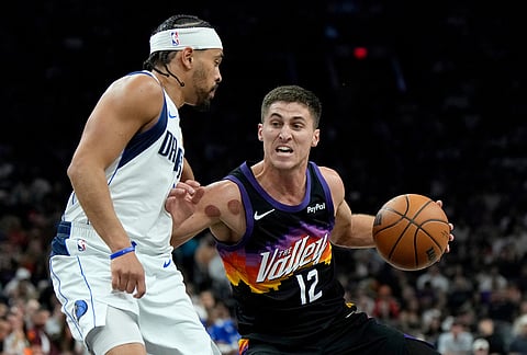Phoenix Suns guard Collin Gillespie (12) dribbles the ball against Dallas Mavericks guard Ryan Nembhard (9) during the first half of an NBA basketball game, in Phoenix.