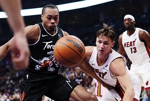 Toronto Raptors' Scottie Barnes, left, and Miami Heat's Pelle Larsson, front right, battle for the ball during first-half NBA basketball game action in Toronto.