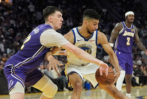 Los Angeles Lakers forward Jake LaRavia, left, reaches for the ball while defending Golden State Warriors forward Malevy Leons during the second half of an NBA basketball game in San Francisco.