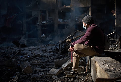 A man sits next to an apartment building destroyed in an Israeli airstrike a day earlier in Beirut, Lebanon, Thursday, April 9, 2026. 
