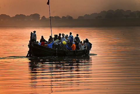 Commuters travel in a boat across the Ganga River at sunset, in Patna.