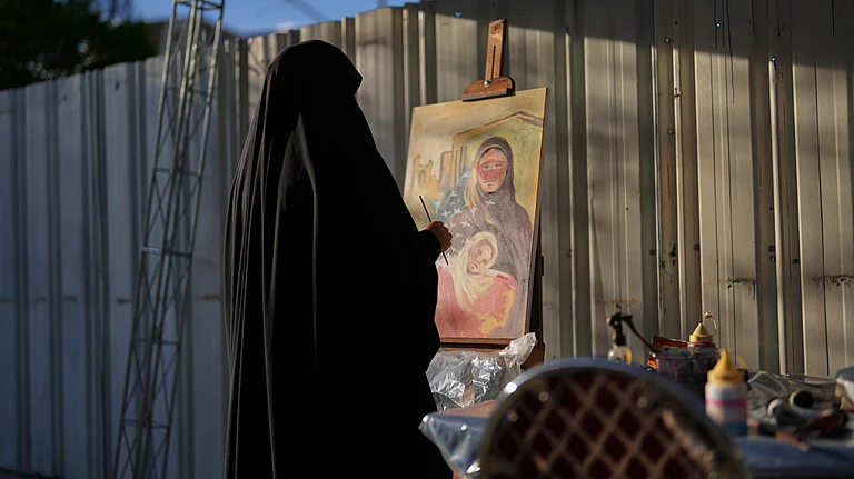 A woman paints a canvas at the site of a concert honoring children killed in a strike on a school in Minab, southern Iran, outside a theater hall in Tehran, Iran, Monday, April 6, 2026. - Francisco Seco