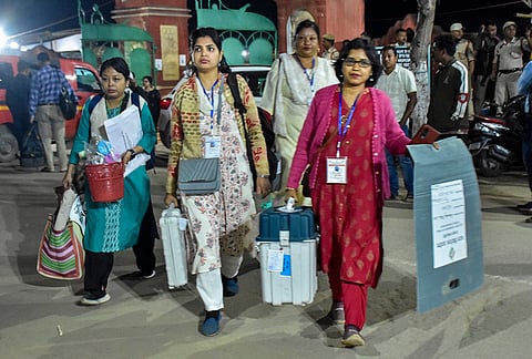 Polling officials carry the sealed Electronic Voting Machines (EVMs) after voting in the Assam Assembly elections, in Sivasagar.