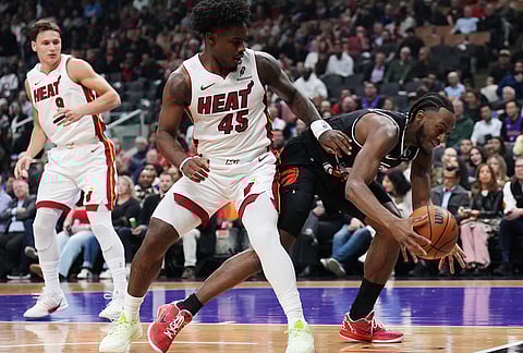 Toronto Raptors' Immanuel Quickley, right, battles for the ball with Miami Heat's Davion Mitchell (45) during first-half NBA basketball game action in Toronto.