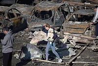 | Photo: AP/Emilio Morenatti : A woman holds her dog as she walks past burned cars a day after an Israeli airstrike in Beirut, Lebanon, Thursday, April 9, 2026. 