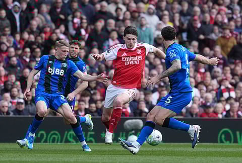 Arsenal's Declan Rice in action between Bournemouth's Adrien Truffert, left, and Marcos Senesi during the Premier League soccer match between Arsenal and Bournemouth in London, England.