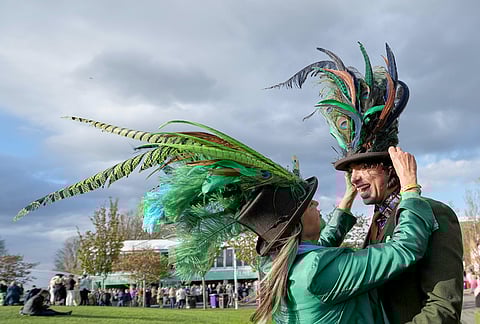 Racegoers adjust their hats on Ladies Day, the second day of the Grand National Horse Racing festival, at Aintree racecourse, near Liverpool, England.