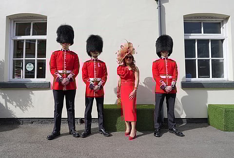 A racegoer poses for a picture with soldiers on Ladies Day, the second day of the Grand National Horse Racing festival, at Aintree racecourse, near Liverpool, England.