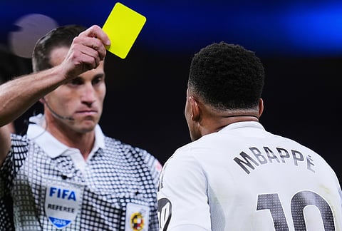 Referee shows a yellow card to Real Madrid's Kylian Mbappe during a Spanish La Liga soccer match between Real Madrid and Girona in Madrid, Spain.