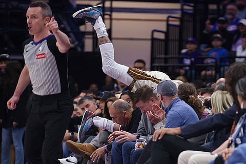 Golden State Warriors forward Gui Santos, behind, falls into the crowd attempts to grab a loose ball during the first half of an NBA basketball game against the Sacramento Kings in Sacramento, Calif.