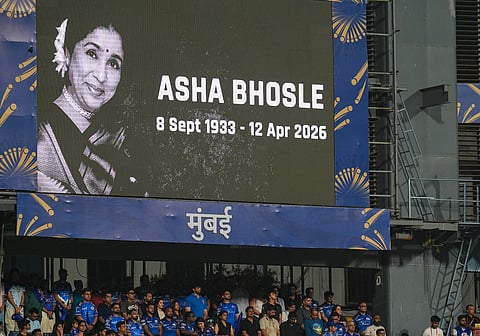 Attendees stand during a moment of silence observed in memoriam of singing legend Asha Bhosle, before an Indian Premier League (IPL) 2026 T20 cricket match between Mumbai Indians and Royal Challengers Bengaluru, in Mumbai, Maharashtra, Sunday, April 12, 2026. Bhosle, India's beloved singing icon, died at the age of 92 on Sunday following multiple organ failure, doctors treating her said. 