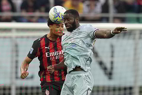 AC Milan's Koni De Winter, left, and Udinese's Keinan Davis jump for the ball during the Serie A soccer match between AC Milan and Udinese, in Milan, Italy.